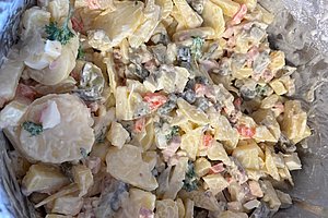 Nahaufnahme eines gemischten Salats mit Kartoffeln, Erbsen, Karotten und Mayonnaise.