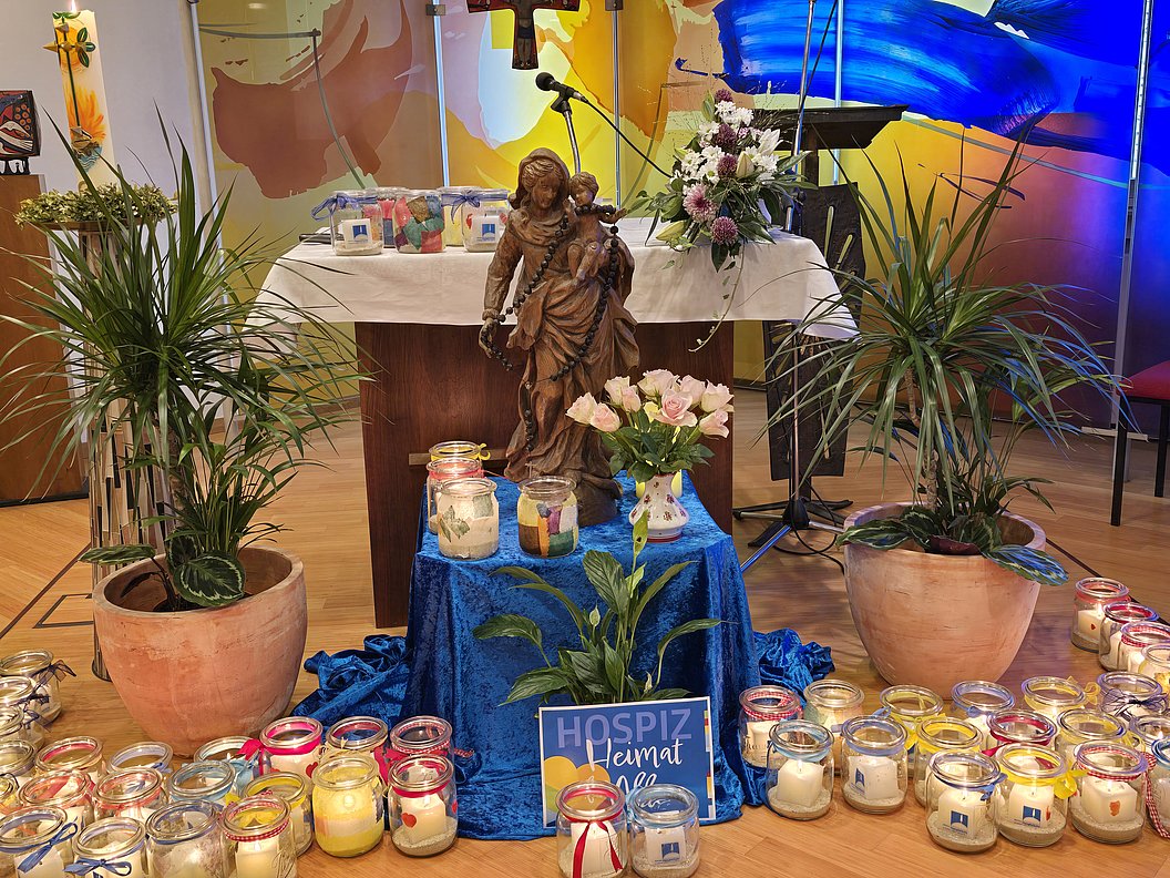 Dekorative Szene mit einer Statue, Pflanzen und Kerzen auf einem Tisch bei einer Feier.