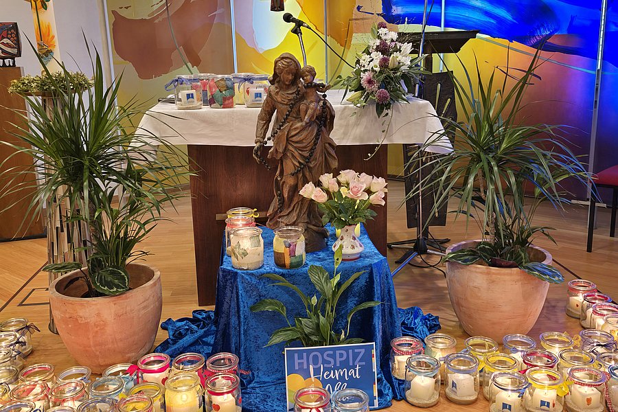 Dekorative Szene mit einer Statue, Pflanzen und Kerzen auf einem Tisch bei einer Feier.