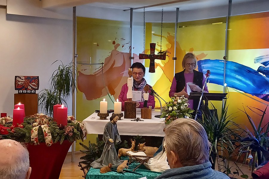 Szenen einer Feier mit zwei Rednern an einem Altar mit Kerzen, Weihnachtsdekoration und Kunsthintergrund.
