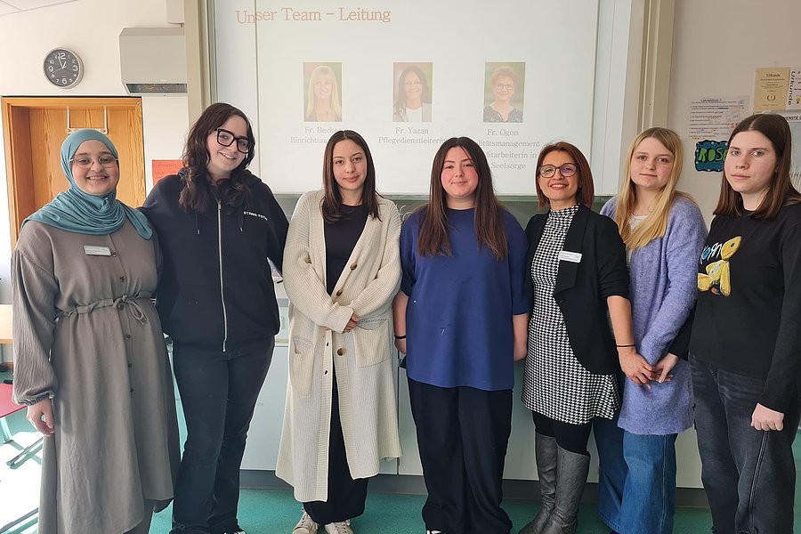 Gruppe von Frauen im Team, stehend vor einer Präsentation im Hintergrund