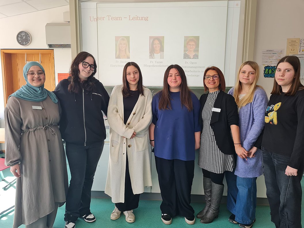 Gruppe von Frauen im Team, stehend vor einer Präsentation im Hintergrund