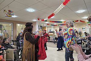 Festliche Stimmung mit Personen in bunten Kostümen bei einer Karnevalsveranstaltung im Seniorenheim.