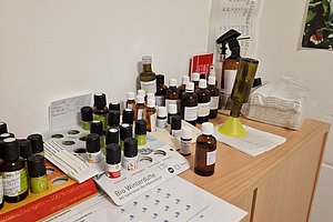 Tisch mit verschiedenen ätherischen Ölen, Anleitungen und anderen Utensilien für Aromatherapie.