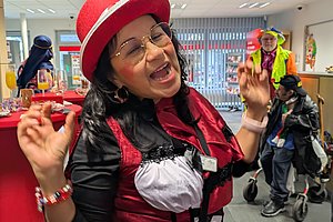 Frau in rotem Hut und Kostüm, die fröhlich posiert und singt