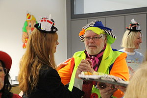 Bunte Feier mit Gästen in festlicher Kleidung und Hüten, die zusammen tanzen und Spaß haben.