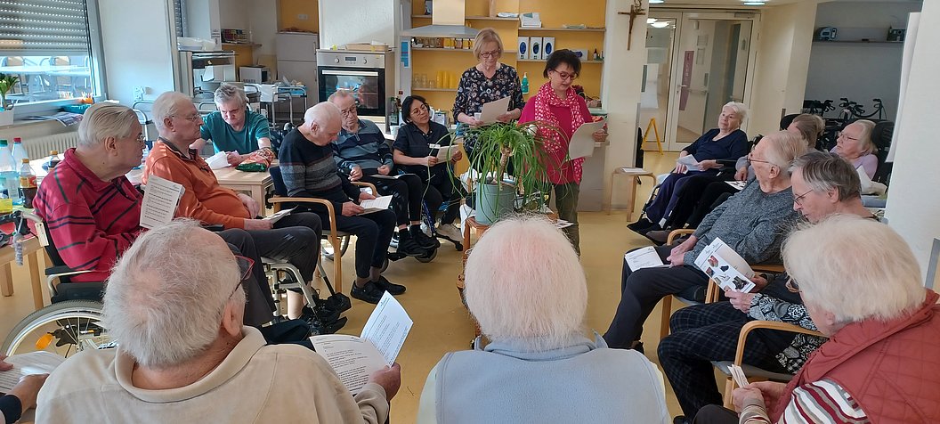 Gruppe von Senioren bei einer Veranstaltung mit einer Präsentation in einem Gemeinschaftsraum.
