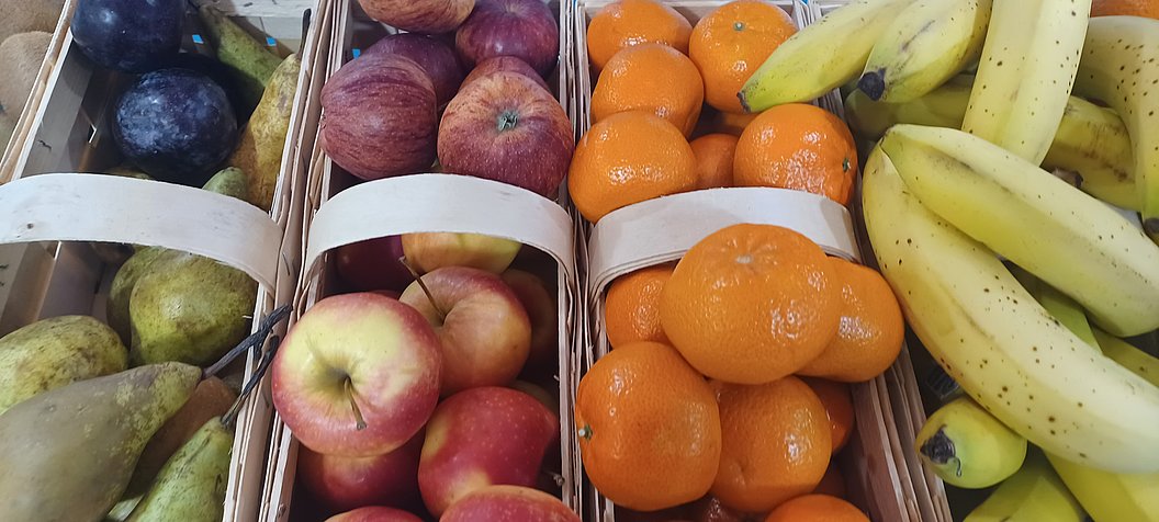 Frisches Obst in Körben: Äpfel, Mandarinen und Bananen auf einem Markt.